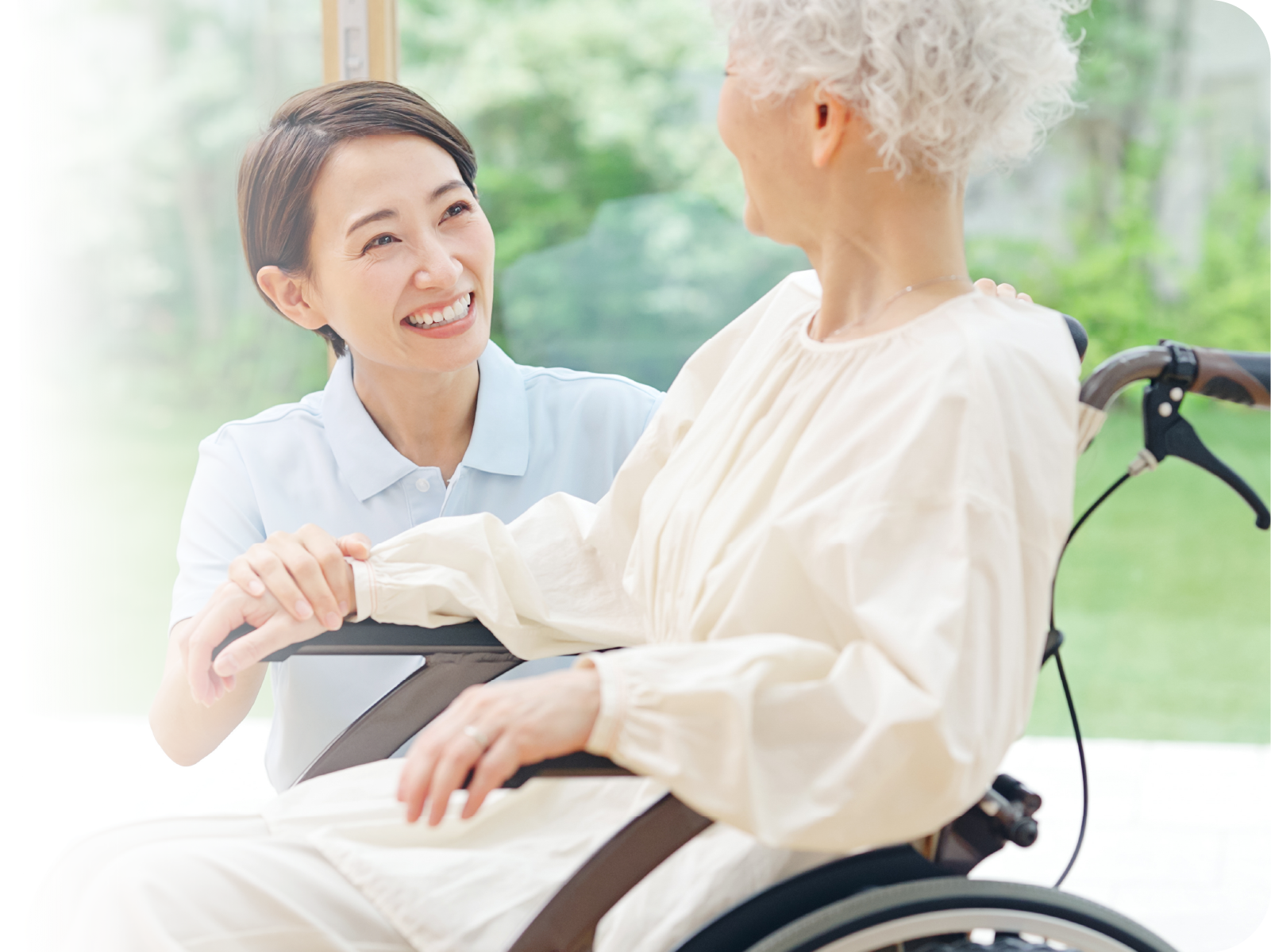 車椅子の入所者様と笑顔で語り合う看護師